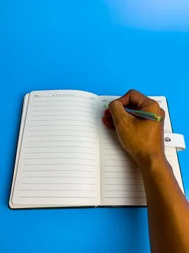 Hand writes in a notebook on a blue background Stock Photos