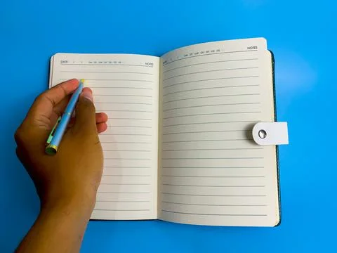 Hand writes in a notebook on a blue background Stock Photos