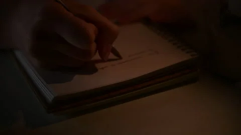 Hand writes in notebook with flickering candle light, writing poetry Stock Footage 156757087
