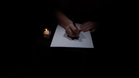 Hand Writes with a Pen on White Paper in a Dark Room by Candlelight Video stock 263799682