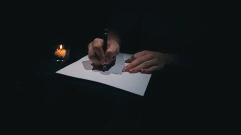 Hand Writes with a Pen on White Paper in a Dark Room by Candlelight Video stock 264110778