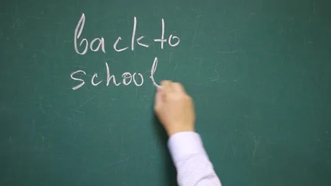 Hand writes the phrase "Back to school" on the school blackboard Vídeo Stock 123670632