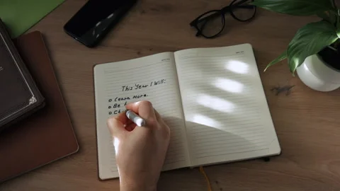 A hand writes a plan for the next year with a black felt-tip pen in a notebook Stock Footage 259821478