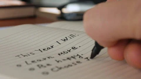 A hand writes a plan for the next year with a black felt-tip pen in a notebook. Stock Footage 259823296