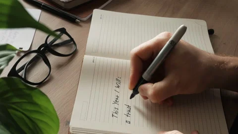 A hand writes a plan for the next year in a notebook. close up Stock Footage 259825061
