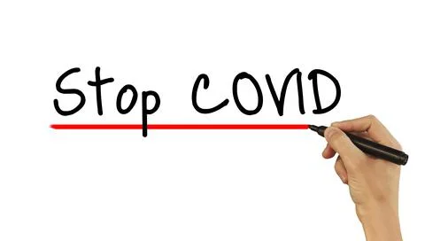 The hand writes text STOP COVID with a marker on a white background Stock Photos