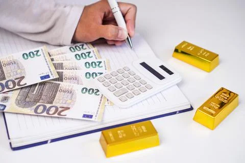 A hand writes with a white pen in a notebook beside a calculator and a row .. Stock Photos