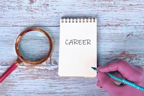 A hand writes the word career in a notepad while a magnifying glass sits near 스톡 사진