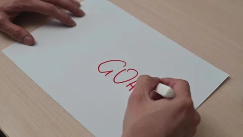 A hand writes the word GOAL in a bold red marker on a blank piece of paper. The 库存影片 337550385