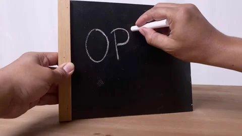 Hand writes the word OPEN on a small blackboard with white chalk Stock Footage 345587096