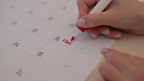 A hand writes the word Rent in red on a calendar date while holding a marker. 库存影片 337556550