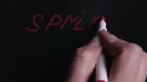 Hand writes the word spring and draws the flower symbol on the Board Stock Footage 145043821