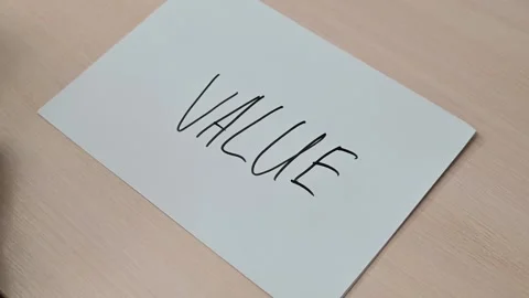 A hand writes the word VALUE on a sheet of paper using a marker, then enhances 스톡 동영상 337549978