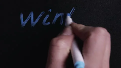 Hand writes the word winter and draws the snowflake symbol on the Board Stock Footage 144964799