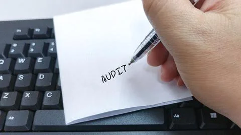Hand writing Audit on a note placed on a computer keyboard Stock Photos