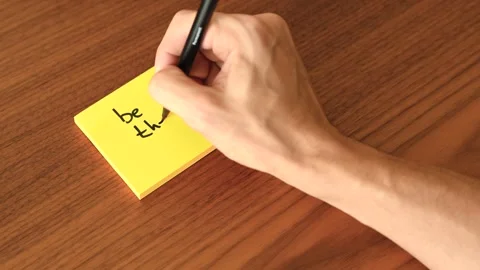 Hand Writing 'be the change' on Sticky Note Stock Footage 328331157