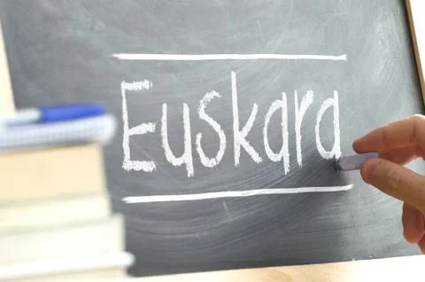 Hand writing on a blackboard in a language class with the word BASQUE Stock Photos