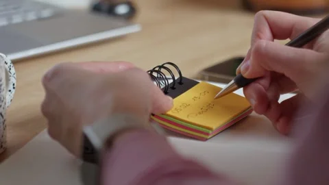 Hand writing a deadline note on small sticky paper pad Stock Footage 328197717