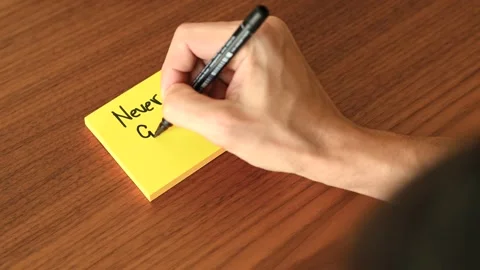Hand Writing 'Never Give Up' on Sticky Note Stock Footage 328331291