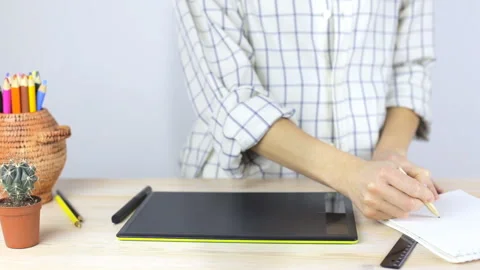 Hand writing in a notebook and draw on the professional graphics tablet Stock Footage 104478795