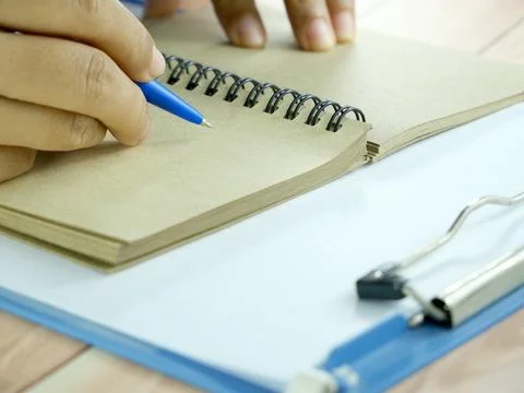 Hand writing in notebook on brown background. Insurance or financial busine.. Stock Photos