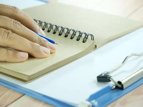 Hand writing in notebook on brown background. Insurance or financial busine.. Stock Photos