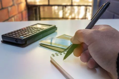 Hand Writing in Notebook with Calculator and Credit Card Nearby, financial Stock Photos
