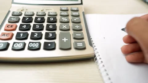 Hand Writing in Notebook Next to Calculator Stock Footage 320724857