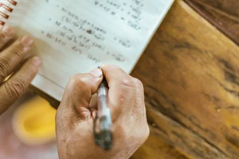A hand writing on a notebook on a table Stock Photos