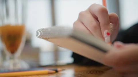 Hand writing in notebook while using smartphone in cozy workspace with warm soft Stock Footage 346635632