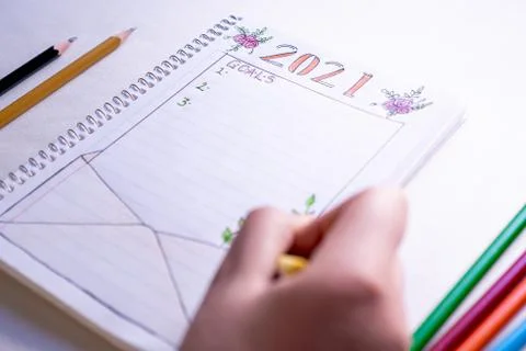 Hand writing in notebook to write New Year's resolutions on a table with a wh Stock Photos