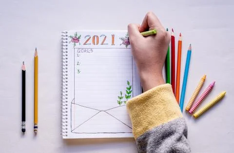 Hand writing in notebook to write New Year's resolutions on a table with colo Stock Photos