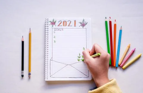 Hand writing in notebook to write New Year's resolutions on a table with colo Stock Photos
