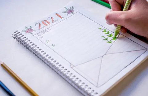 Hand writing in notebook to write New Year's resolutions on a table with a wh Stock Photos