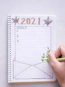 Hand writing in notebook to write New Year's resolutions on a table with a wh Stock Photos