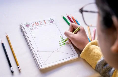 Hand writing in notebook to write New Year's resolutions on a table with colo Stock Photos