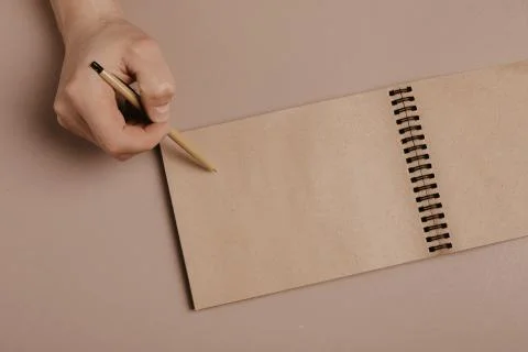 Hand writing in notepad using a pen, on gray background Stock Photos