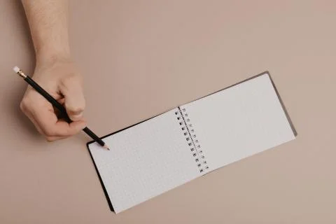 Hand writing in notepad using a pencil, on gray background Stock Photos
