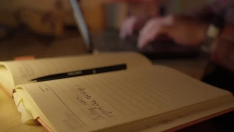Hand Writing Notes in Notebook at Desk in Warm Light Stock Footage 344946810