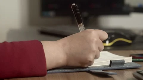Hand Writing Notes with Pen on Wooden Desk, Close-up Shot Stockbeeldmateriaal 334711952