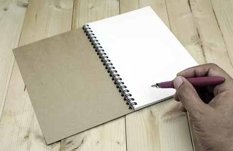 Hand writing in open notebook on table Stock Photos