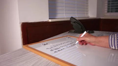 Hand writing out meeting schedule on whiteboard Stock Footage 346771920