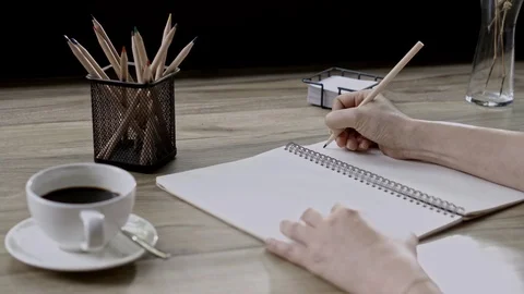 Hand writing the pencil to in book with table, view of room on the morning Stock Footage 106492878