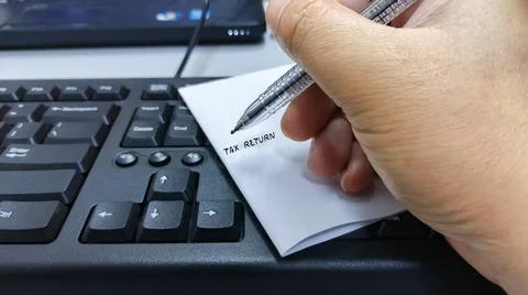 Hand writing Tax Return on a note placed on a computer keyboard Stock Photos