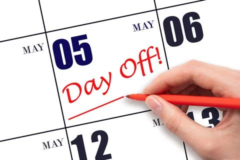 Hand writing text DAY OFF and drawing a line on calendar date 5 May. Vacation Stock Photos