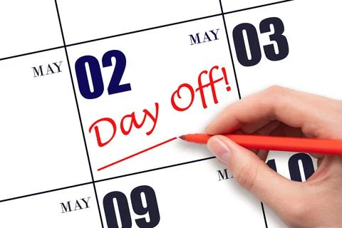 Hand writing text DAY OFF and drawing a line on calendar date 2 May. Vacation Stock Photos