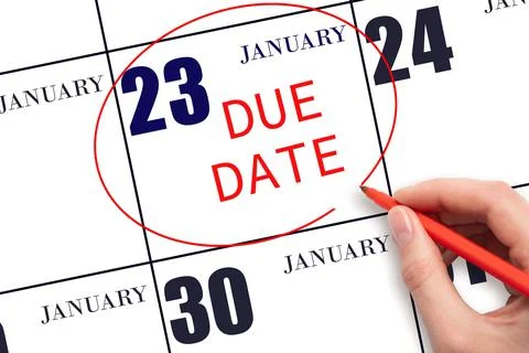 Hand writing text DUE DATE on calendar date January 23 and circling it. Payme Stock Photos