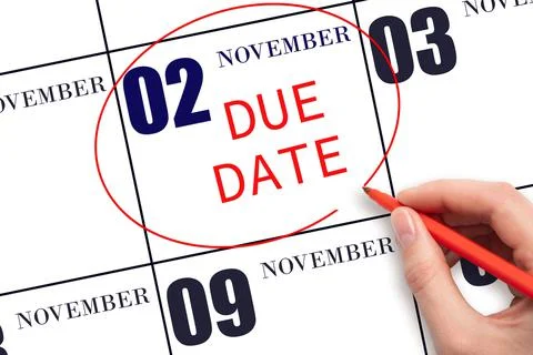 Hand writing text DUE DATE on calendar date November 2 and circling it. Payme Stock Photos