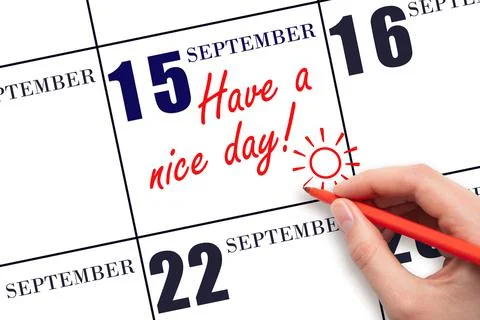 The hand writing the text Have a nice day and drawing the sun on the calendar Stock Photos
