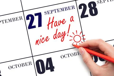 The hand writing the text Have a nice day and drawing the sun on the calendar Stock Photos
